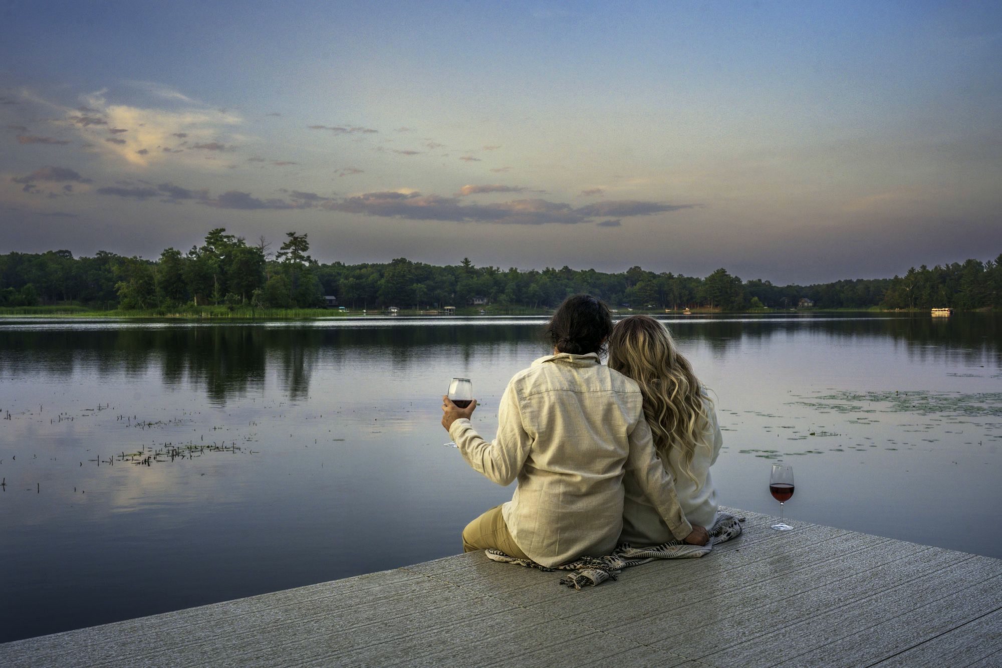 Golden hour on the dock — this is the whole point Couple sharing a glass of wine at sunset on a private dock in Crosslake, MN